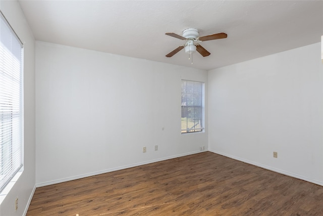 empty room with dark wood-style floors, plenty of natural light, baseboards, and a ceiling fan