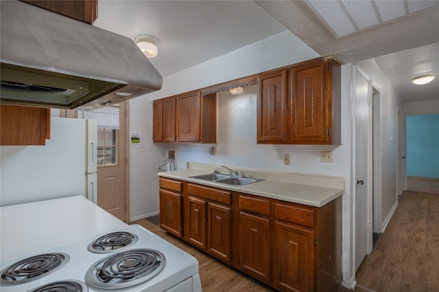 kitchen featuring island range hood, white appliances, a sink, light countertops, and brown cabinets