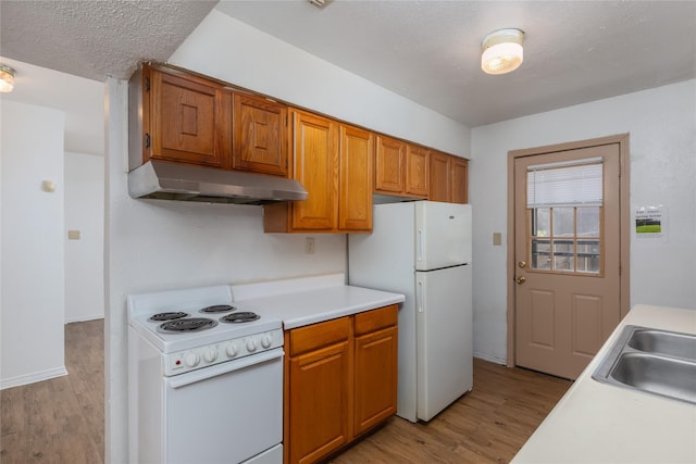 kitchen with white appliances, light countertops, a sink, and under cabinet range hood