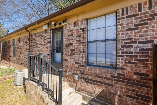 property entrance featuring brick siding and central air condition unit