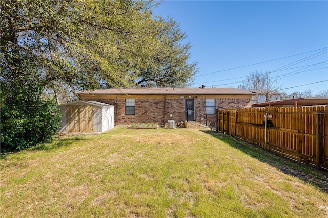 back of house with brick siding, a lawn, a storage shed, central AC unit, and fence