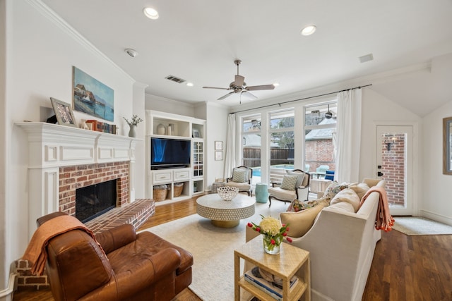 living area featuring a fireplace, ornamental molding, and wood finished floors