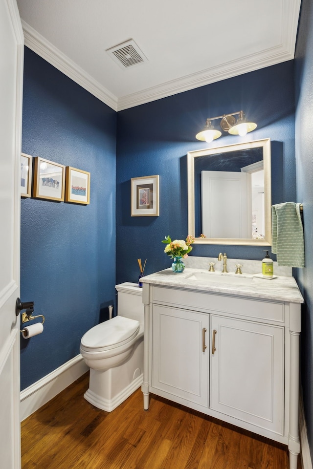 bathroom featuring toilet, wood finished floors, vanity, visible vents, and baseboards