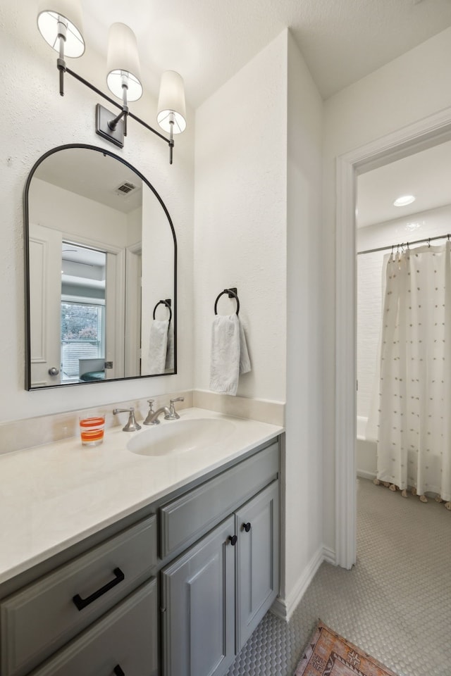 bathroom with shower / bath combination with curtain, visible vents, and vanity