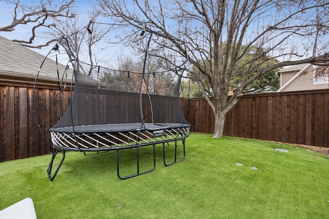 view of yard with a trampoline and fence