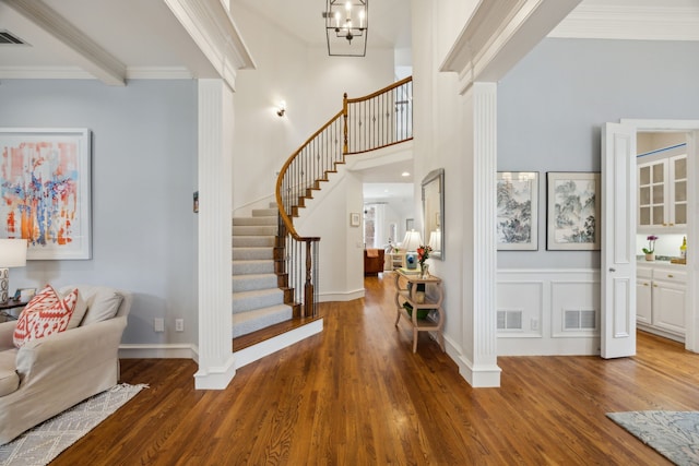 foyer with dark wood-type flooring, visible vents, crown molding, and stairs