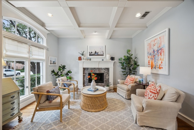 living area with visible vents, coffered ceiling, a premium fireplace, light wood-type flooring, and beam ceiling