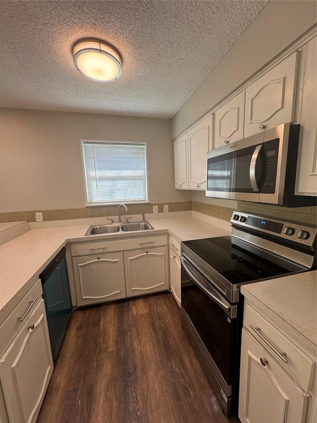 kitchen featuring stainless steel appliances, light countertops, dark wood-type flooring, white cabinetry, and a sink