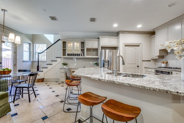 kitchen with a sink, white cabinetry, hanging light fixtures, open shelves, and a kitchen bar