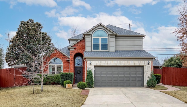 traditional home with an attached garage, fence, and a front yard