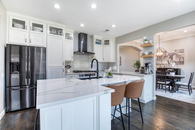 kitchen with white cabinets, wall chimney range hood, glass insert cabinets, and stainless steel appliances