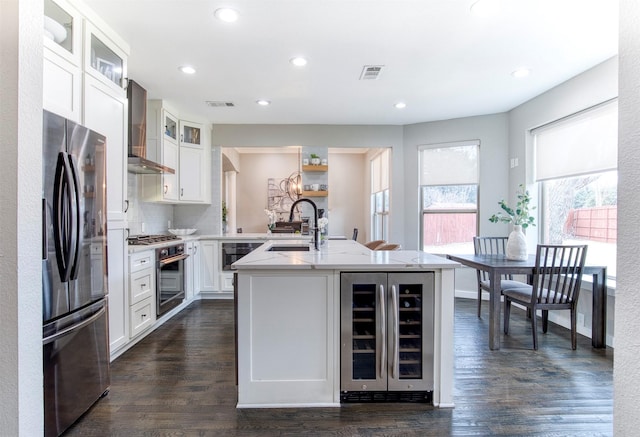 kitchen with a center island with sink, wine cooler, glass insert cabinets, appliances with stainless steel finishes, and a sink