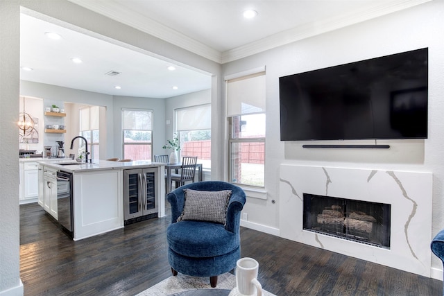 interior space with wine cooler, a center island with sink, light countertops, white cabinetry, and a sink