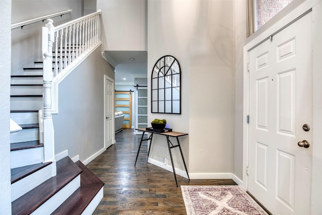 entryway with dark wood finished floors, stairway, baseboards, and a barn door