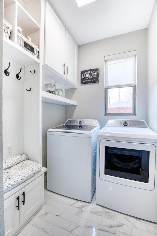 clothes washing area featuring marble finish floor, cabinet space, and washer and clothes dryer