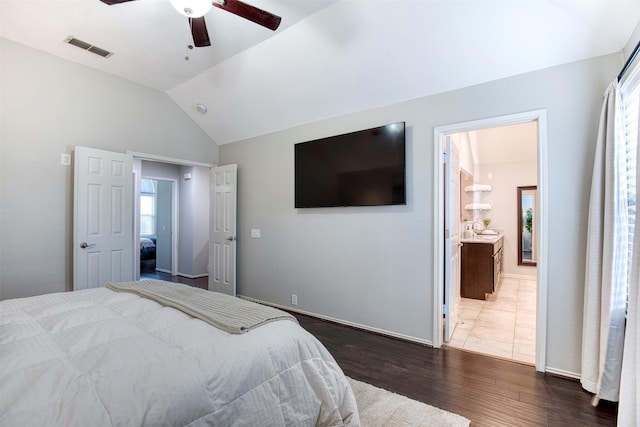 bedroom featuring lofted ceiling, wood finished floors, visible vents, a ceiling fan, and ensuite bath