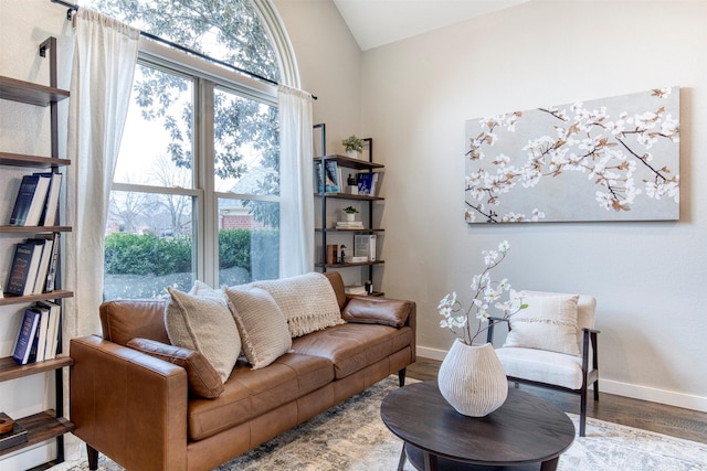 living room featuring vaulted ceiling, light wood-style flooring, and baseboards