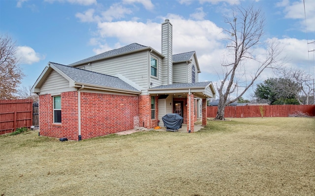 back of property with a yard, brick siding, a chimney, and fence private yard