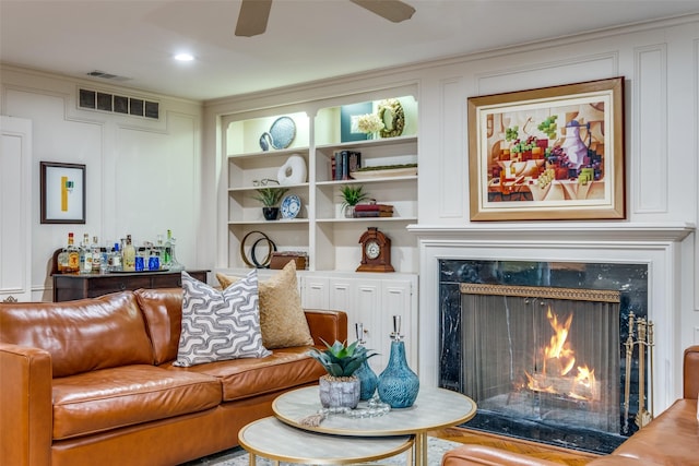 living room with ceiling fan, built in shelves, a fireplace, and visible vents