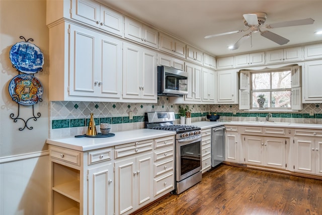 kitchen with dark wood-style floors, stainless steel appliances, tasteful backsplash, light countertops, and a sink