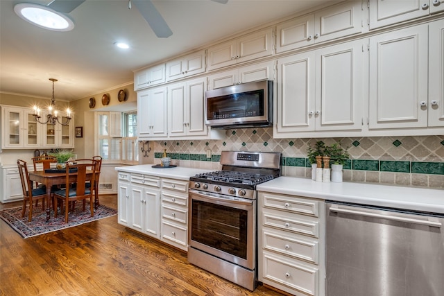 7131 Lakehurst Ave, Dallas, TX 75230 - kitchen featuring backsplash, appliances with stainless steel finishes, light countertops, dark wood-style floors, and glass insert cabinets
