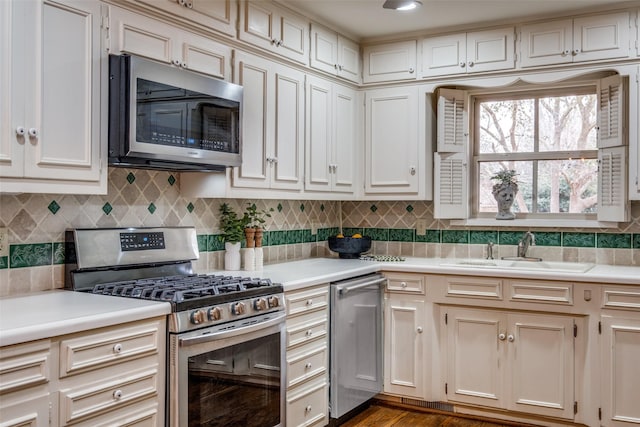 kitchen featuring a sink, backsplash, stainless steel appliances, and light countertops