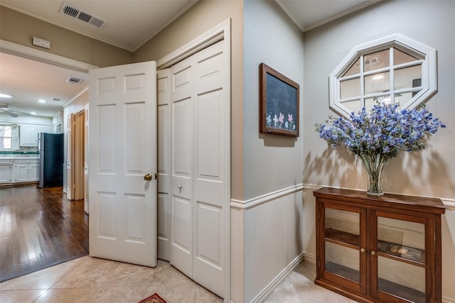 hallway featuring light tile patterned floors, ornamental molding, and visible vents