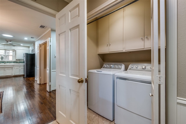 laundry room featuring washer and clothes dryer, cabinet space, visible vents, a ceiling fan, and wood finished floors