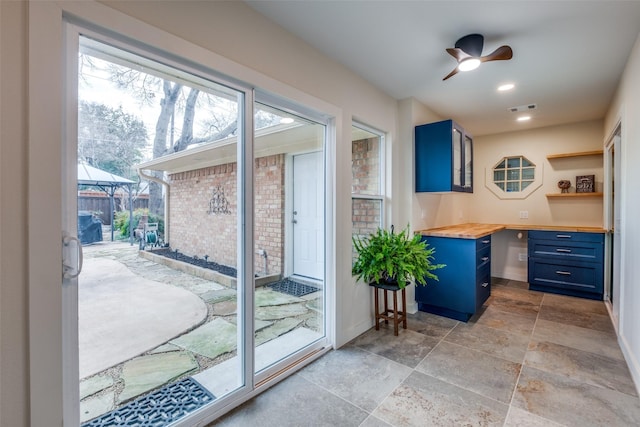 doorway featuring recessed lighting, a ceiling fan, visible vents, baseboards, and stone finish floor