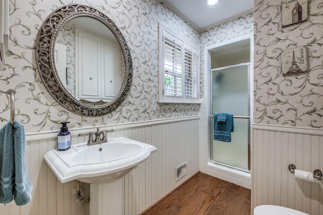 bathroom with a stall shower, wainscoting, and wallpapered walls