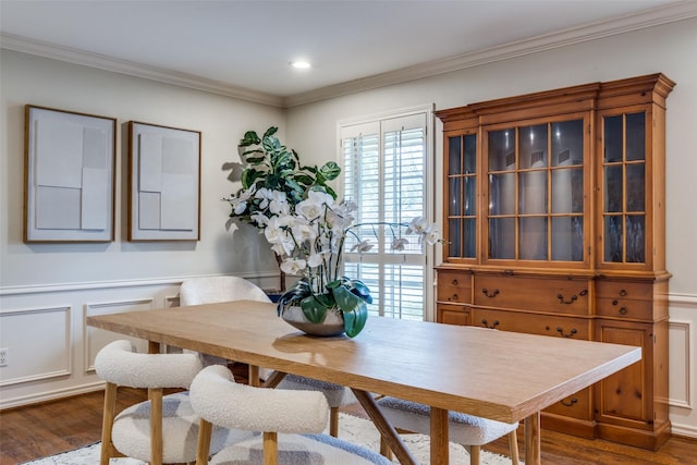 dining room with a wainscoted wall, crown molding, a decorative wall, and wood finished floors