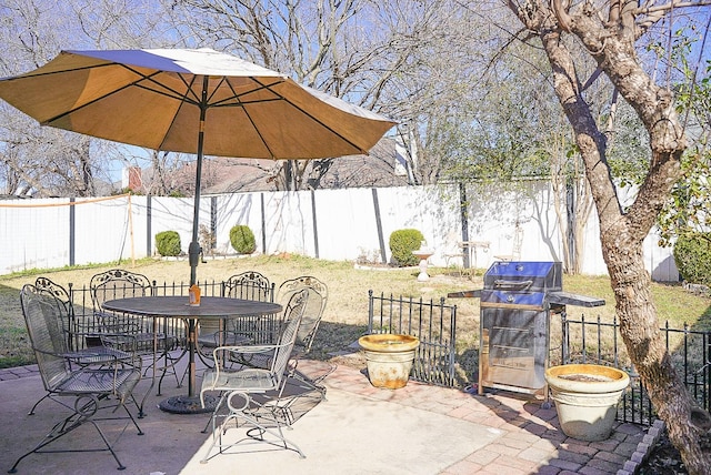 view of patio with outdoor dining area, grilling area, and a fenced backyard