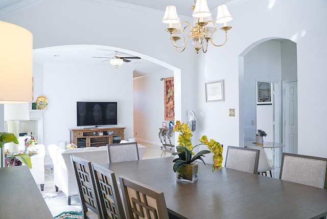 dining space featuring arched walkways, crown molding, and ceiling fan with notable chandelier