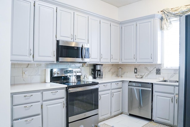 kitchen featuring stainless steel appliances, gray cabinets, light countertops, and decorative backsplash