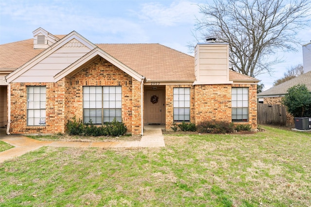 ranch-style house featuring a front yard, brick siding, and central AC