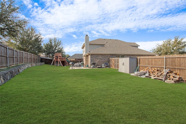 view of yard featuring an outbuilding, a playground, a fenced backyard, a shed, and a patio area
