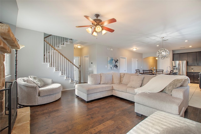 living area with stairs, dark wood-style flooring, recessed lighting, baseboards, and ceiling fan with notable chandelier