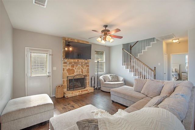 living room featuring plenty of natural light, visible vents, dark wood finished floors, and a stone fireplace