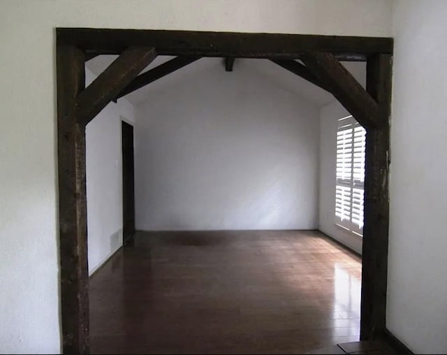 additional living space featuring lofted ceiling with beams and dark wood-style floors