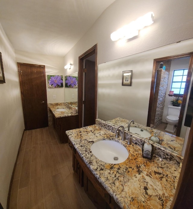 full bath with two vanities, a sink, and wood finished floors