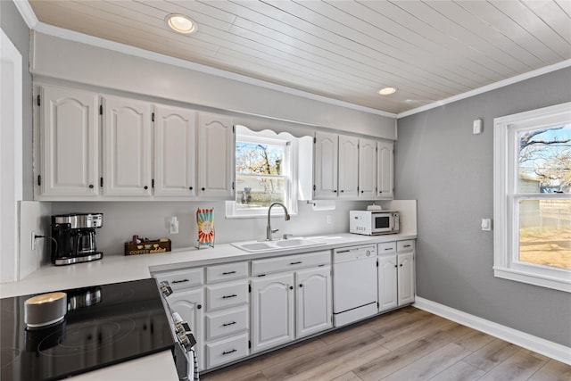 kitchen with crown molding, light countertops, white cabinets, a sink, and white appliances