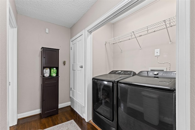 clothes washing area with laundry area, baseboards, dark wood-type flooring, a textured ceiling, and washing machine and dryer