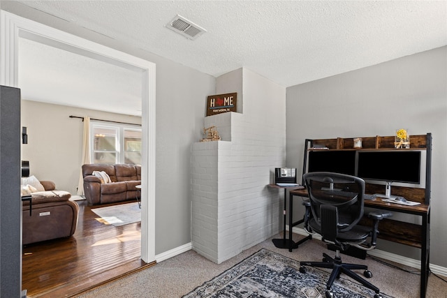 home office featuring a textured ceiling, carpet flooring, visible vents, and baseboards