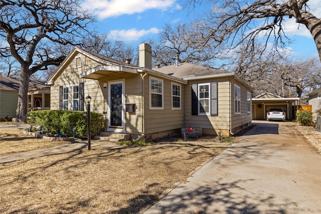 bungalow featuring concrete driveway, a chimney, and roof with shingles