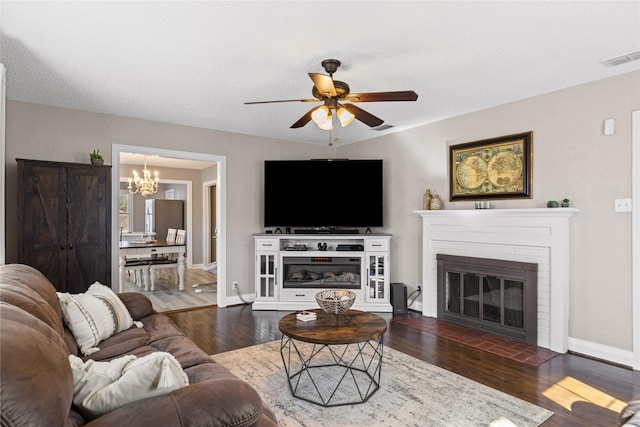 living room with a brick fireplace, baseboards, visible vents, and dark wood-type flooring