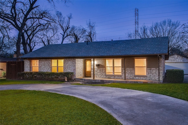 single story home with stone siding, a front lawn, and a shingled roof