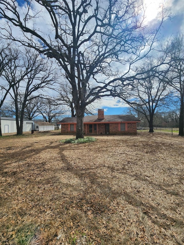 view of front of home with brick siding, fence, and a chimney