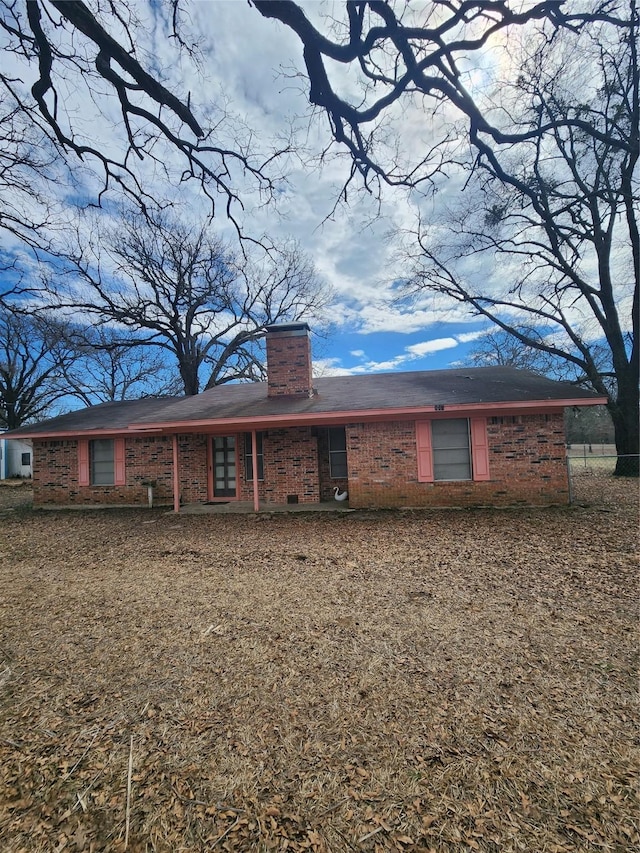 back of property featuring a chimney and brick siding