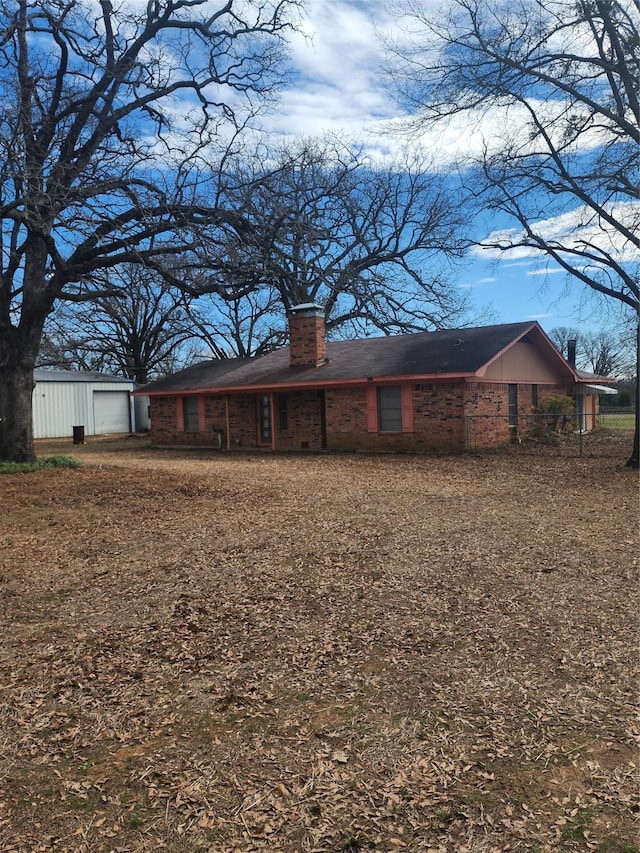 rear view of house with a garage, brick siding, and a chimney