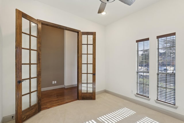 empty room with a ceiling fan, french doors, light carpet, and baseboards